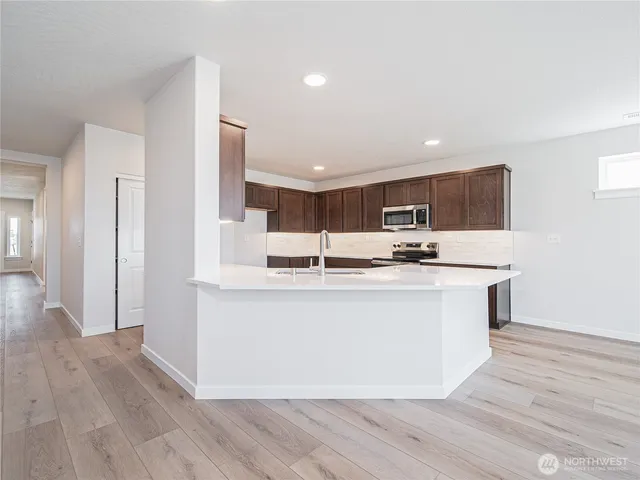 a view of kitchen with stainless steel appliances granite countertop stove top oven and refrigerator
