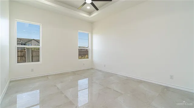 an empty room with a ceiling fan and windows