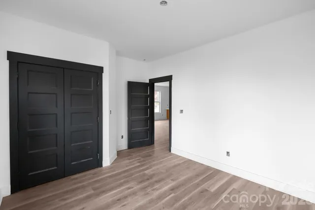 a view of an empty room with closet and wooden floor