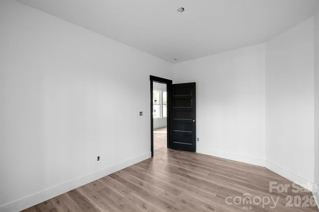 a view of an empty room with wooden floor and closet