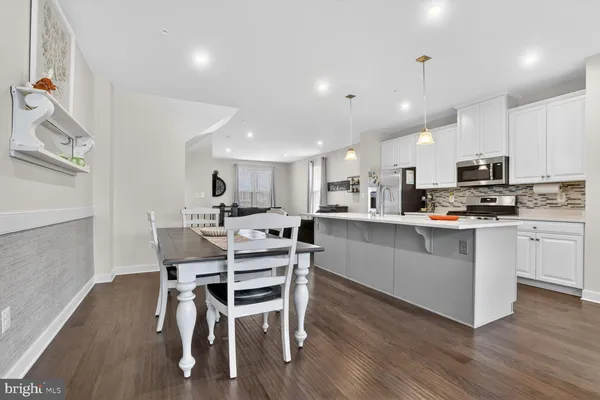a kitchen with white cabinets stainless steel appliances and dining table