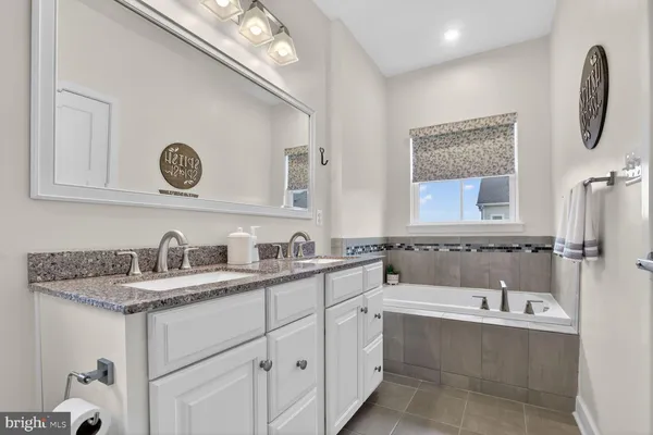 a bathroom with a granite countertop sink mirror toilet and bathtub