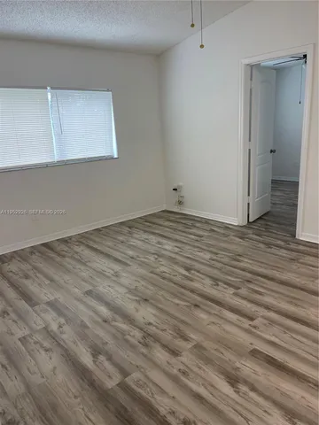 a view of an empty room with wooden floor and cabinet