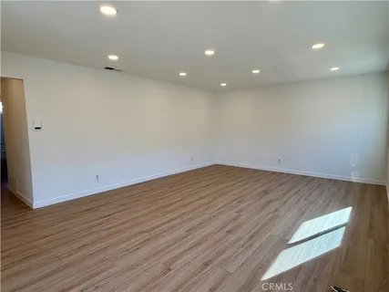 an empty room with wooden floor and entrance