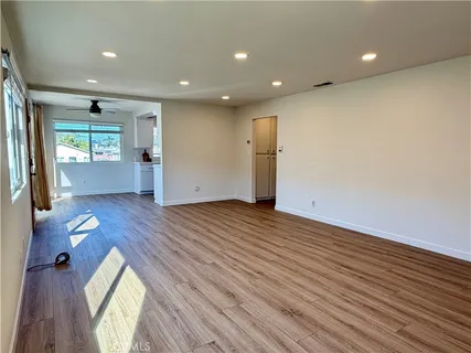 a view of empty room with wooden floor and fan