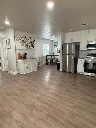 a large kitchen with stainless steel appliances wooden floors and a large window