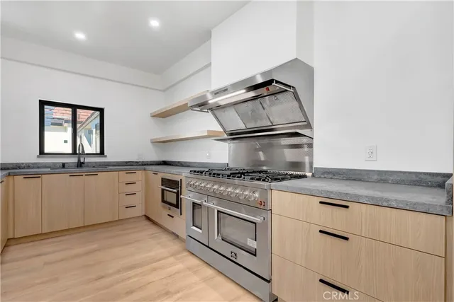 a view of an empty room with a window and kitchen view