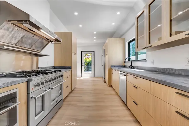 a view of an empty room with kitchen and window