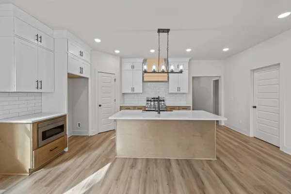 a large white kitchen with wooden floor