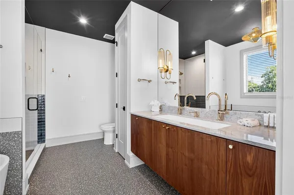 a spacious bathroom with a double vanity sink toilet mirror and shower