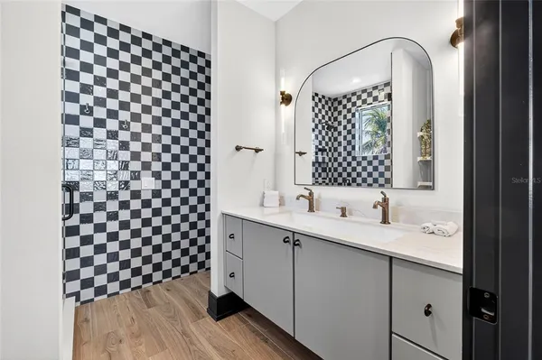 a bathroom with a sink a mirror a vanity and a shower