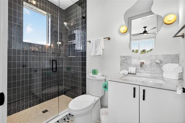 a bathroom with a granite countertop sink a toilet and shower