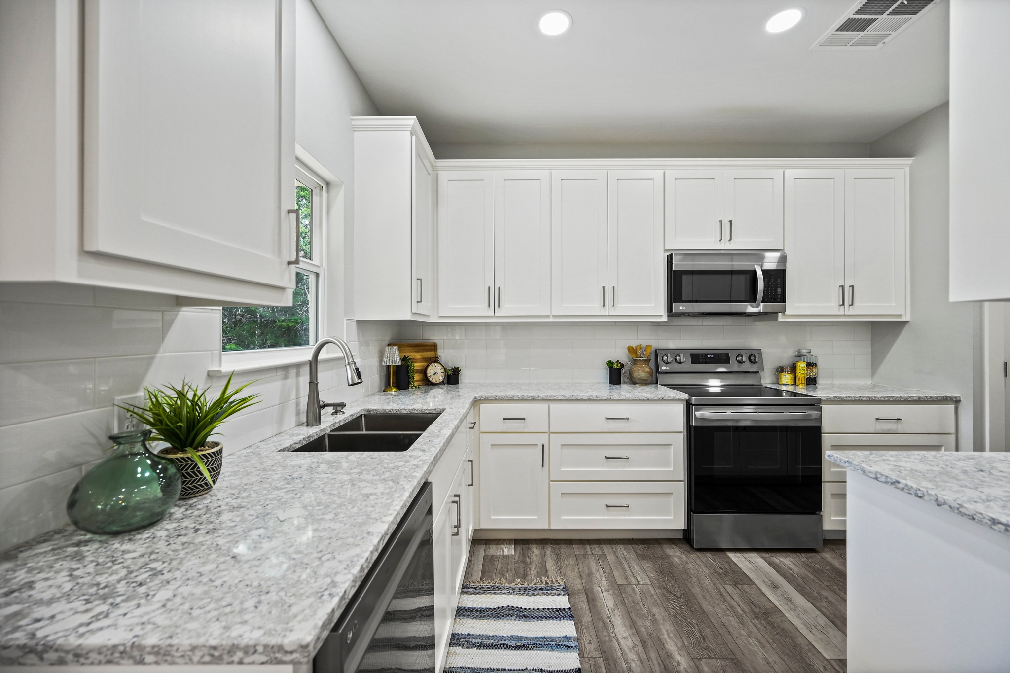 231 North Rainbow Ranch Road Wimberley, TX 78676 - Photo 14 of 40 A well-appointed kitchen features ample white cabinetry, gleaming countertops, and modern appliances.