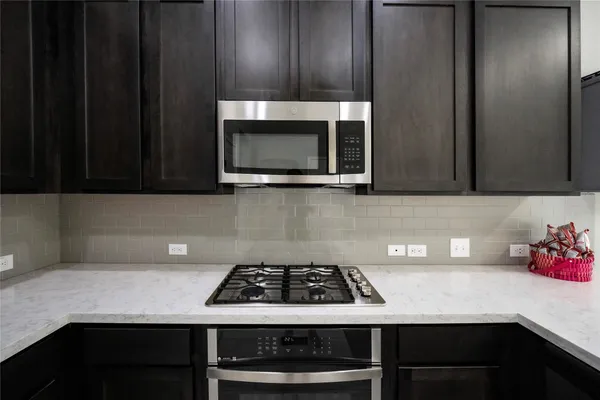 a kitchen with granite countertop cabinets stove top oven and microwave