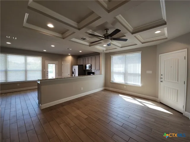 an empty room with wooden floor and windows