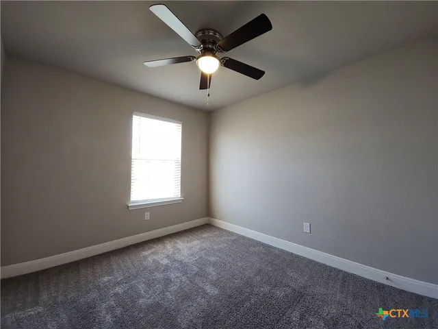 an empty room with a window and a fan