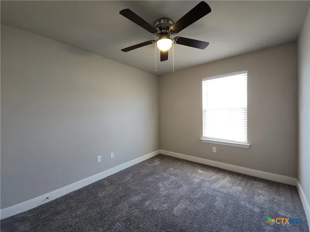 an empty room with a window and a fan
