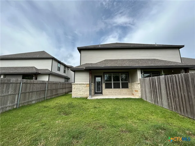 a view of a house with a yard and wooden fence