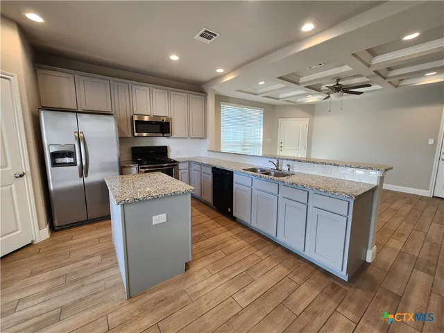 a kitchen with kitchen island a counter top space a sink stainless steel appliances and cabinets