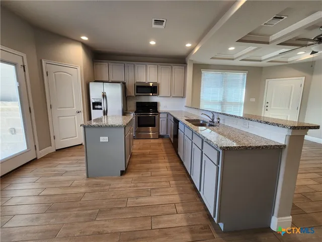 a kitchen with stainless steel appliances granite countertop a refrigerator a stove a sink and a microwave
