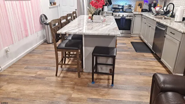 a kitchen with stainless steel appliances kitchen island granite countertop a table chairs in it and wooden floors