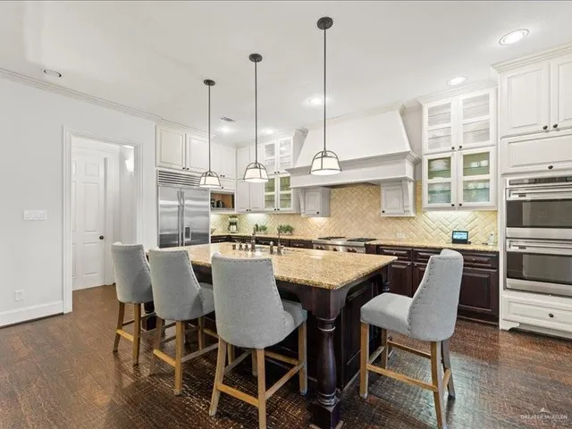 a room with stainless steel appliances granite countertop a stove a sink dishwasher and a dining table with the living room view