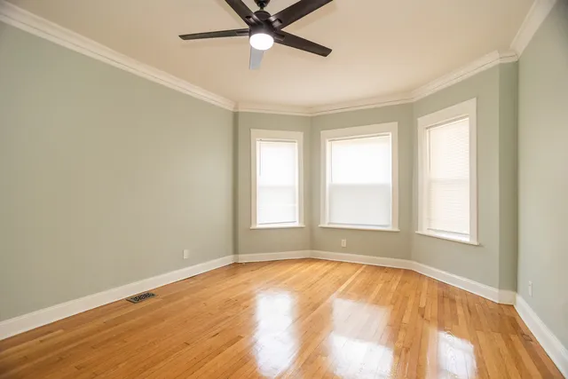 an empty room with a window and ceiling fan