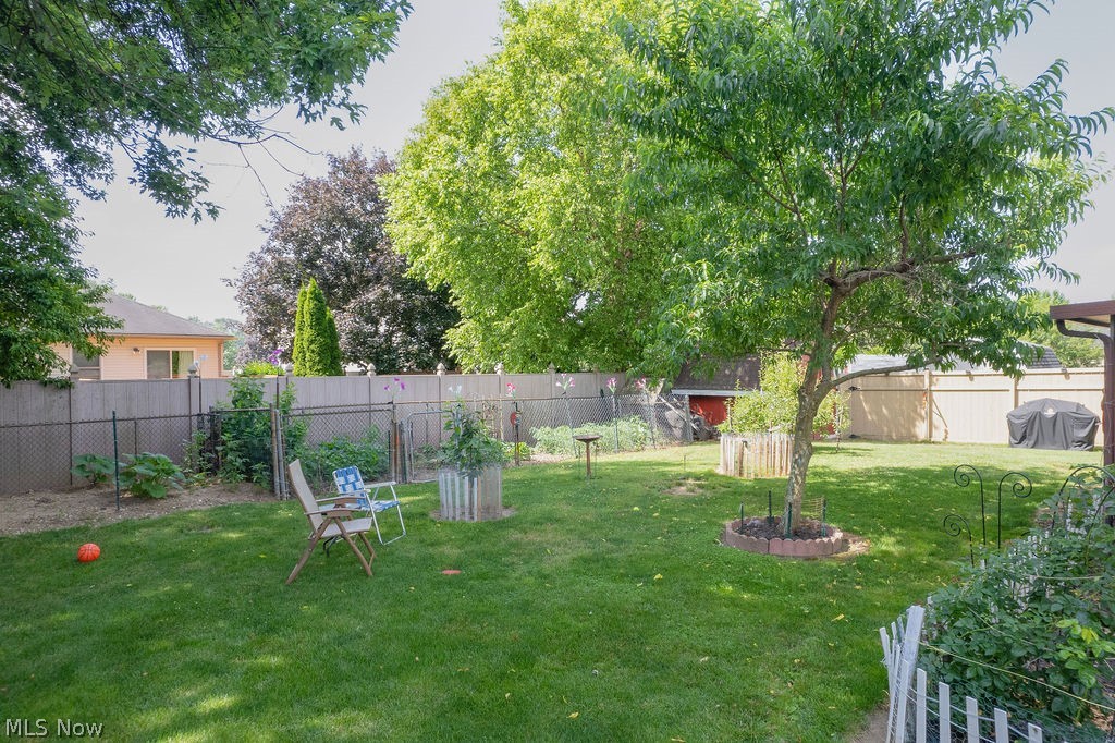 38667 Chestnut Ridge Road Elyria, OH 44035 - Photo 33 of 35 Expansive backyard featuring a lush lawn, mature trees, and a combination of wood and chain-link fencing