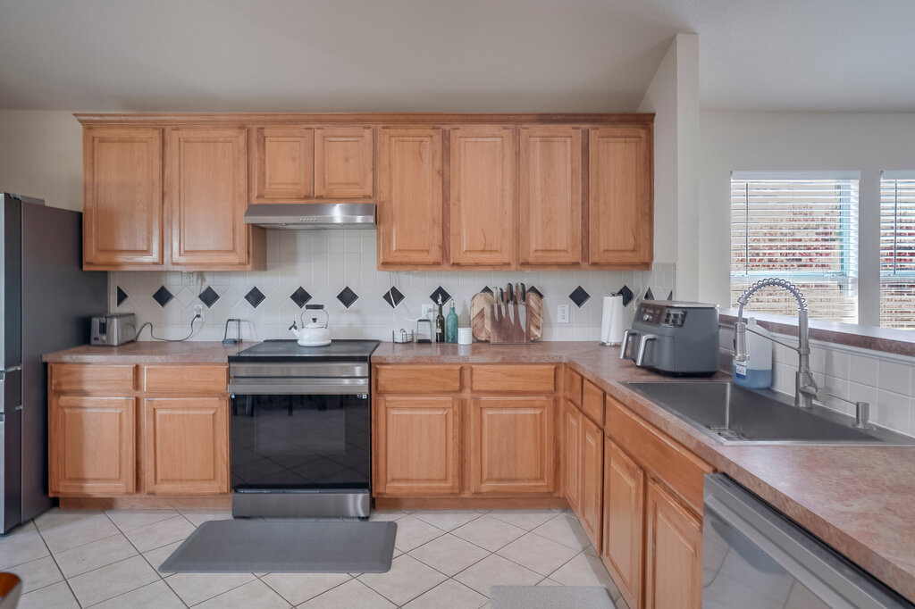 2724 Kickapoo Cavern Drive Pflugerville, TX 78660 - Photo 10 of 24 A well-equipped kitchen features wooden cabinetry and tiled flooring, ideal for culinary creations.