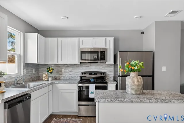 a kitchen with kitchen island granite countertop white cabinets and stainless steel appliances