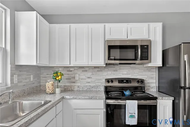 a kitchen with stainless steel appliances granite countertop white cabinets a stove top oven a sink and dishwasher