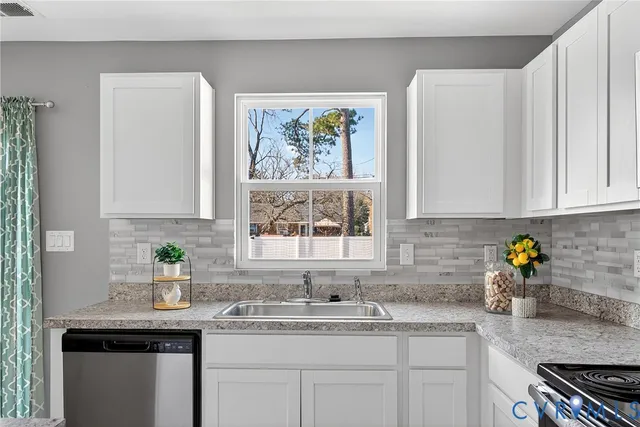 a kitchen with stainless steel appliances granite countertop white cabinets a sink and a window