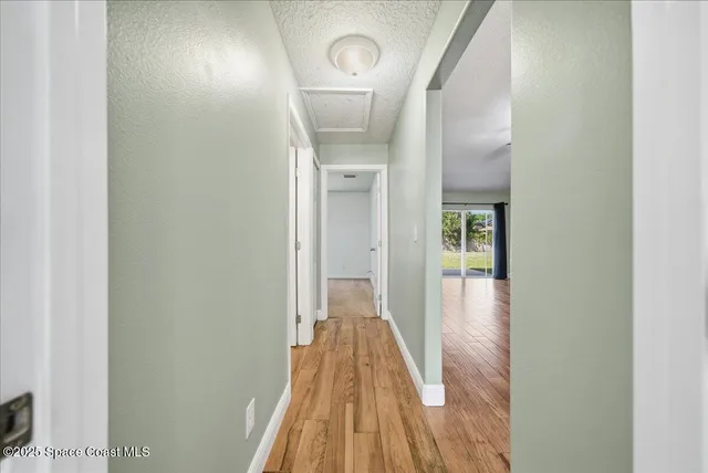 a view of a hallway with wooden floor and a bathroom