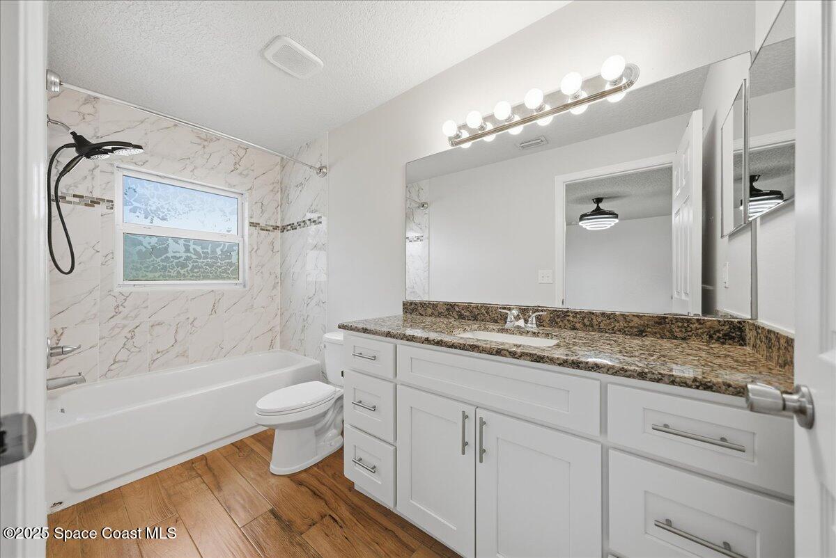 6424 Muller Avenue Cocoa, FL 32927 - Photo 7 of 33 a bathroom with a granite countertop sink a toilet a mirror a bathtub and shower