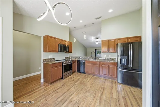 a large kitchen with a large counter top stainless steel appliances and wooden floor
