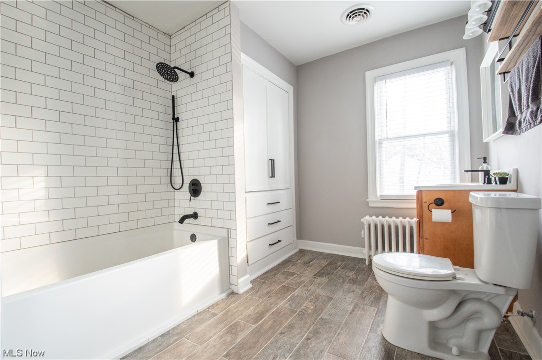 739 Som Center Road Cleveland, OH 44143 - Photo 27 of 36 Full bathroom featuring vanity, hardwood / wood-style floors, tiled shower / bath combo, toilet, and radiator heating unit