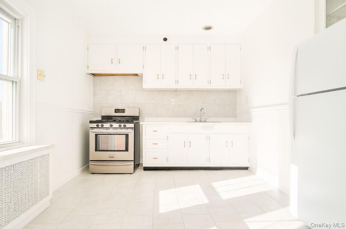 194 Summit Avenue, Unit 2 Mount Vernon, NY 10550 - Photo 1 of 19 Kitchen featuring freestanding refrigerator, stainless steel gas range oven, radiator, light countertops, and white cabinetry