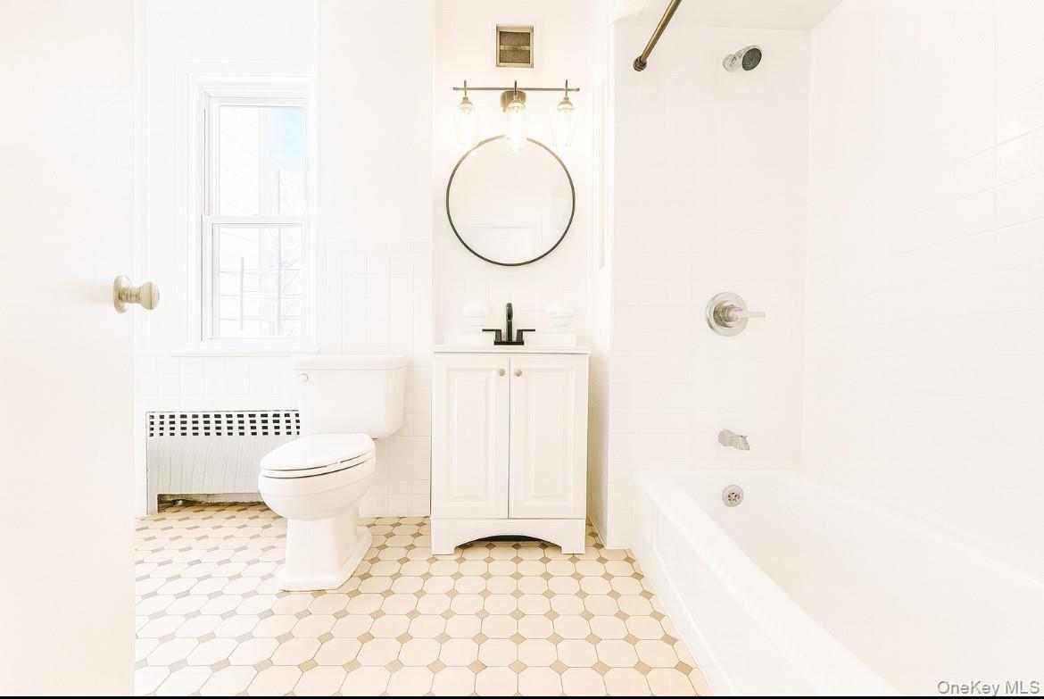 194 Summit Avenue, Unit 2 Mount Vernon, NY 10550 - Photo 2 of 19 Bathroom with radiator, shower combination, vanity, tile walls, and a wainscoted wall