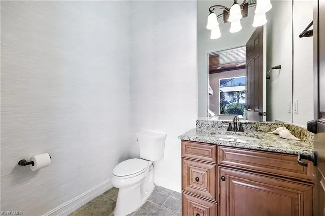 a bathroom with a granite countertop sink vanity mirror and toilet
