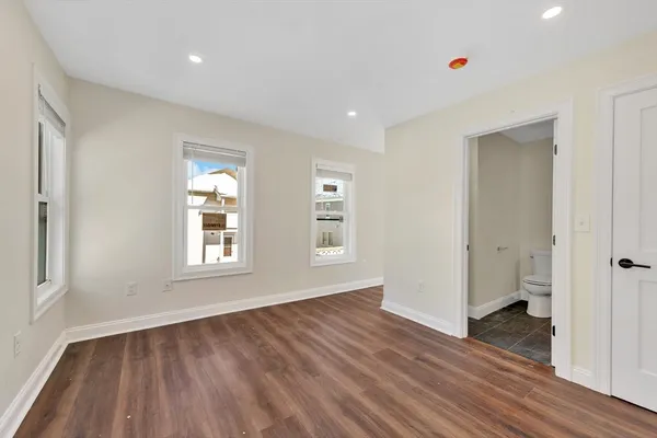 a view of an empty room with wooden floor and windows