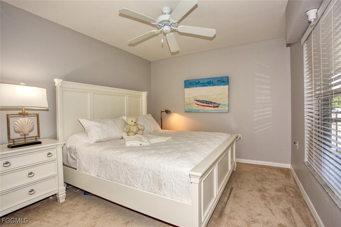 10371 McArthur Palms Lane, Unit 2823 Fort Myers, FL 33966 - Photo 19 of 48 a bedroom with a bed and a chandelier fan