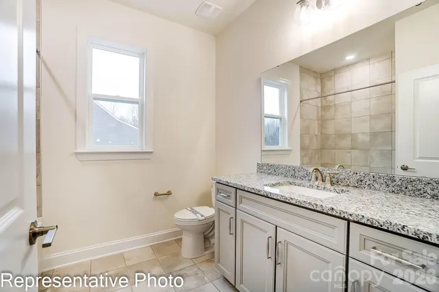 a bathroom with a granite countertop sink a toilet and a mirror