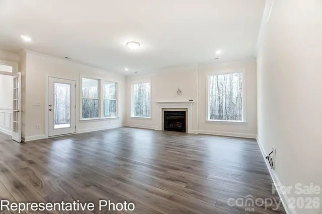 an empty room with wooden floor fireplace and windows
