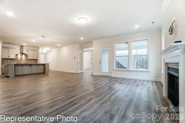 an empty room with wooden floor and a kitchen
