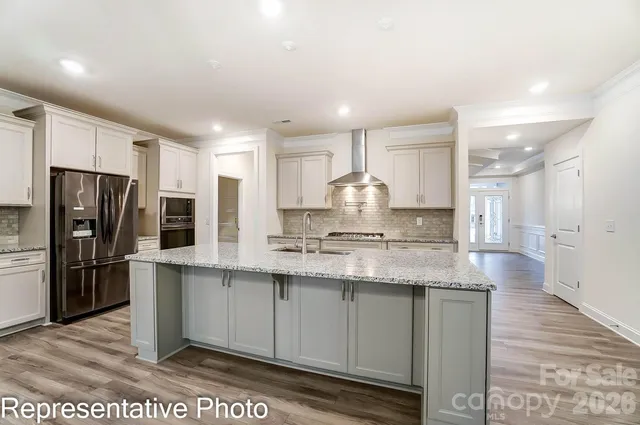 a large kitchen with stainless steel appliances kitchen island granite countertop a refrigerator and a sink