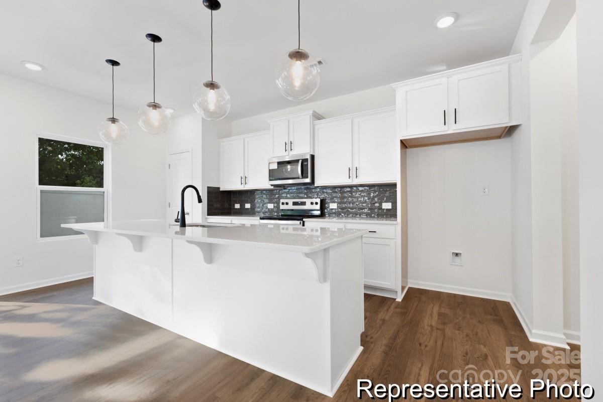 1015 Gondola Court, Unit 21AP Salisbury, NC 28146 - Photo 5 of 22 a kitchen with stainless steel appliances granite countertop a sink a stove a refrigerator and white cabinets with wooden floor