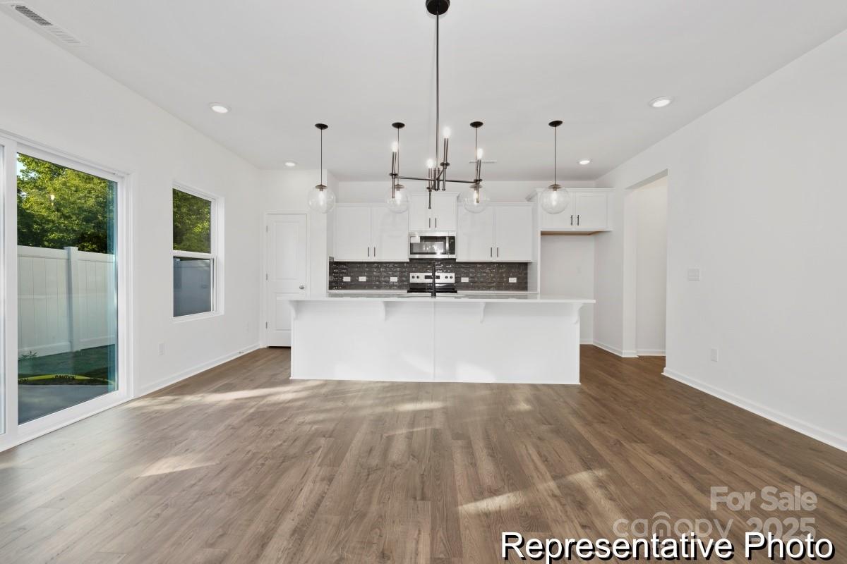 1015 Gondola Court, Unit 21AP Salisbury, NC 28146 - Photo 7 of 22 a large kitchen with stainless steel appliances granite countertop a large stove a refrigerator a oven and white cabinets with wooden floor