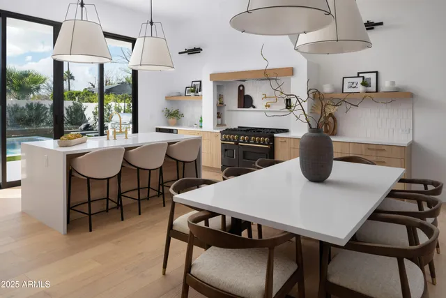 a kitchen with stainless steel appliances granite countertop a stove a sink dishwasher a dining table and chairs with wooden floor