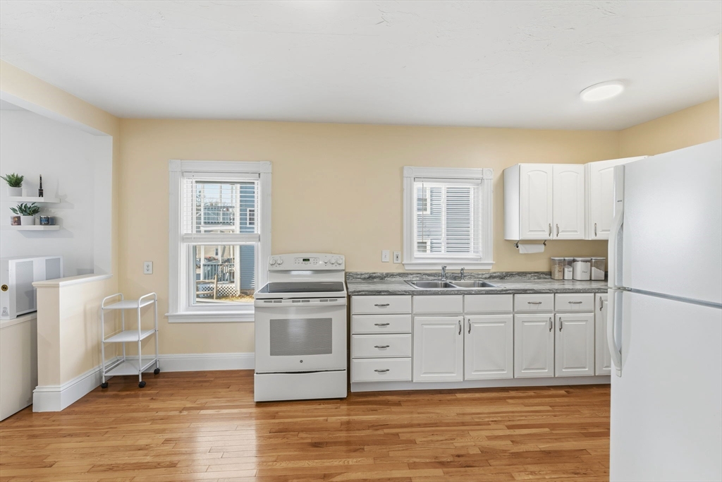 17 Cutler Street, Unit 1 Webster, MA 01570 - Photo 11 of 33 a kitchen with granite countertop a stove a sink and white cabinets with wooden floor