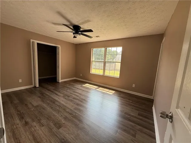 an empty room with wooden floor closet and windows
